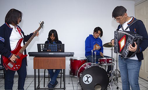 Alumnos tocando bajo, teclado, batería y acordeón